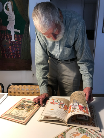 A picture of Lionel Kalish flipping through a book called The Cat and the Fiddler illustrated by Lionel Kalish in the late 1960's